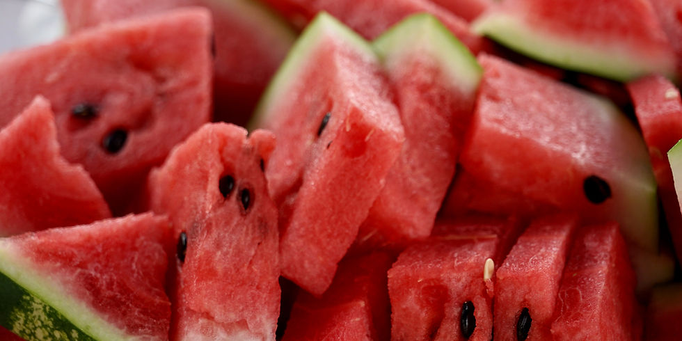 Close-up of sliced watermelon pieces, showing vibrant red flesh with black seeds and a hint of green rind, creating a fresh, summery feel.