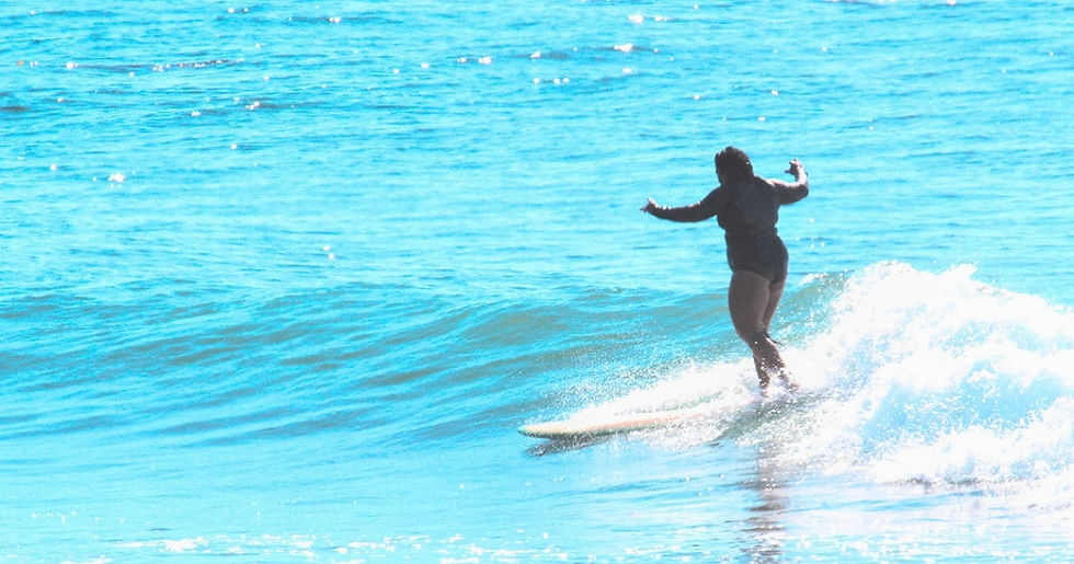 Laura Day mid-cross-step, reaching toward the nose of her longboard