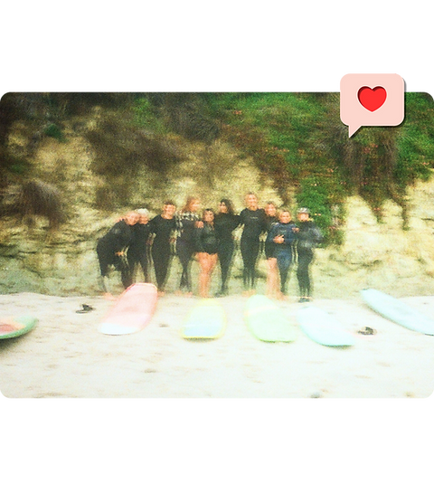 Women surfers standing together on the beach with surfboards.