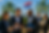 Vier Unternehmer im Business-Casual tauschen sich bei einem Networking-Event unter Palmen und paraguayischer Flagge aus, Skyline von Asunción im Hintergrund.