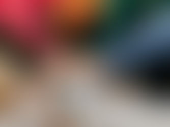 Hands of diverse individuals in colorful sweaters overlap in a supportive gesture outdoors, symbolizing unity and teamwork.