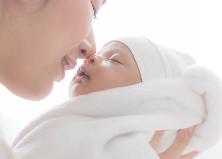 A beautiful Asian woman carried her newborn baby and kiss with happiness after having a lo