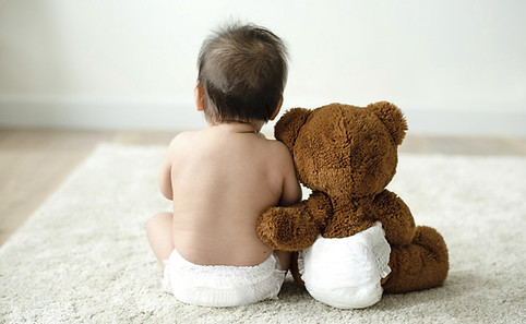 un bebé con un osito de espaldas, un abrazo entre amigos