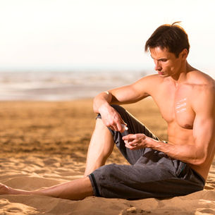 Hombre usando protector solar en la playa.