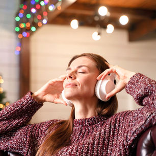 Mujer escuchando con audífonos en época navideña.