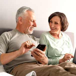 Pareja de adultos mirando aplicaciones en sus dispositivos.