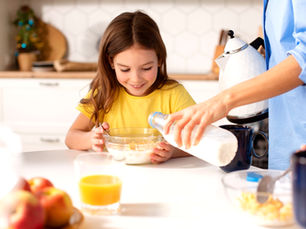Madre sirviendo leche a su hija.