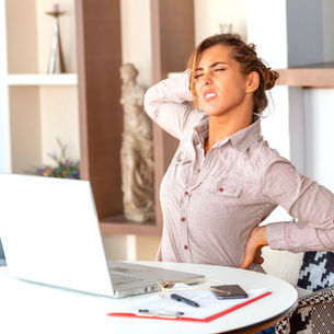 Mujer estirándose en su puesto de trabajo.