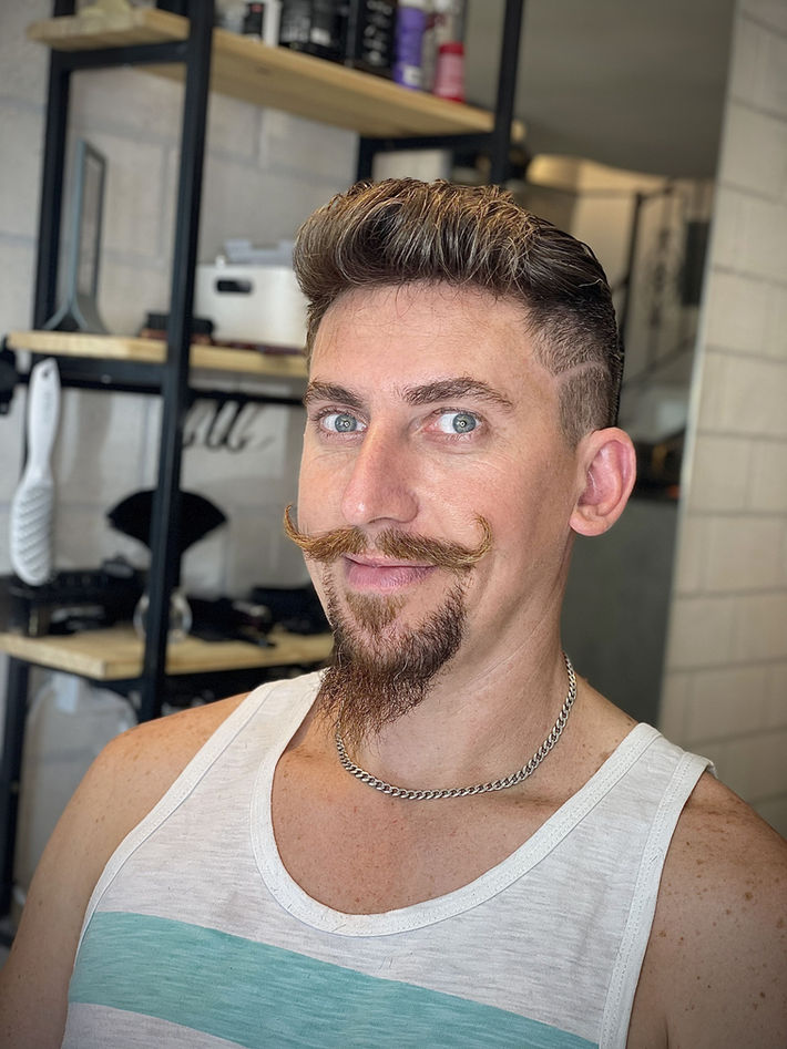 תספורת גבר מודרנית עם קו תספורת חד ושפם מתעגל