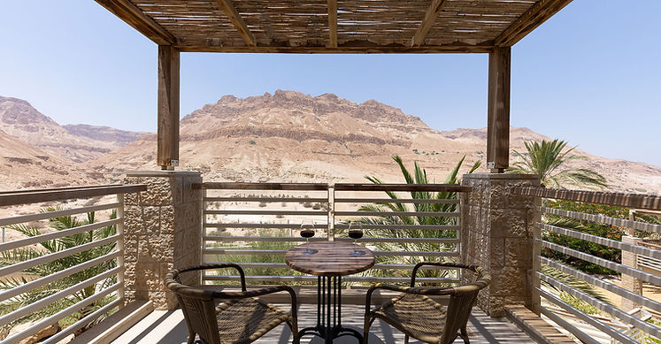 Desert oasis balcony view: table, chairs, mountains. Ein Gedi Hotel