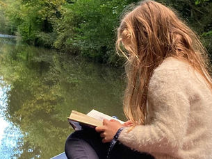 Child reading a book during a family narrowboat day on the Grand Union Canal