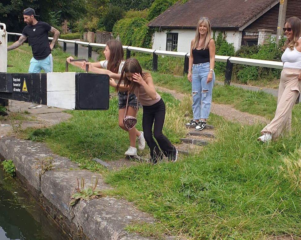 Family aboard a private narrowboat after navigating a lock on the Grand Union Canal.