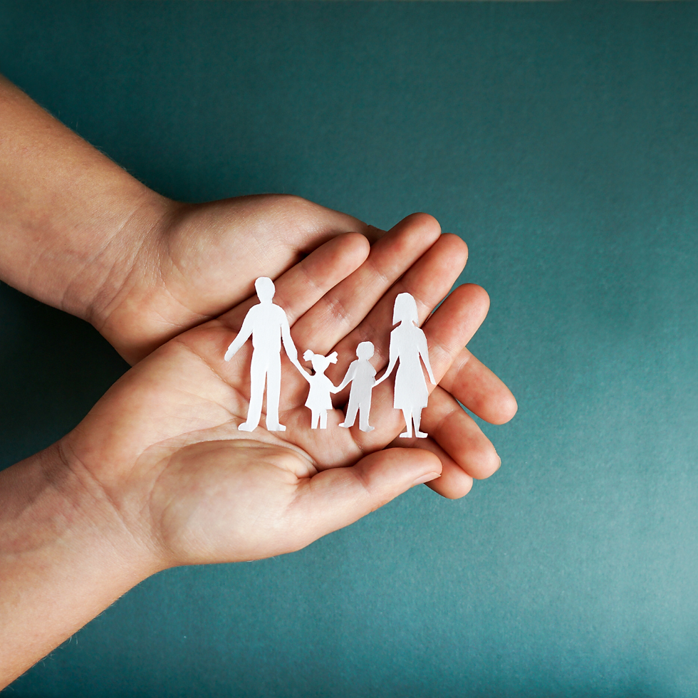 hands gently holding a cutout of a family
