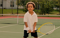 Young boy holding a tennis racket, ready to hit the tennis ball