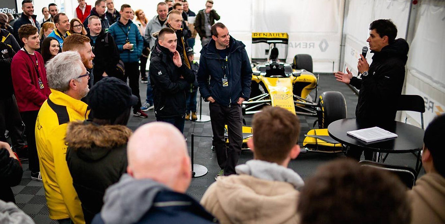 Un instructeur faisant un brief autour d'une Formule 1