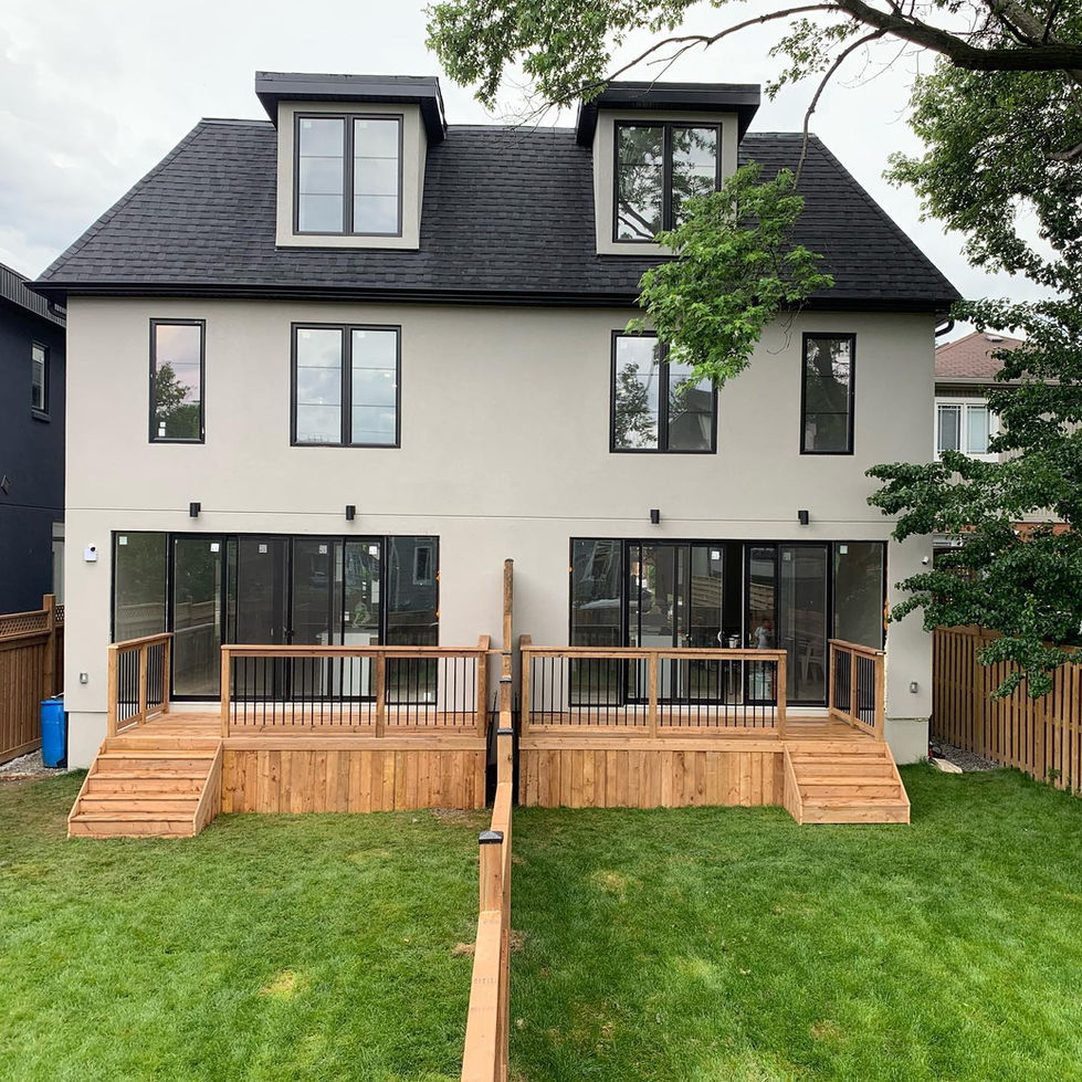 Residential backyard deck made from pressure-treated lumber featuring black metal railings and clean wood skirting design.