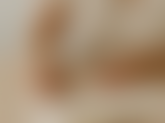 A softly lit, minimalist photograph of a woman writing in an open cream-colored journal on a wooden table. She wears a light beige top, and her hands rest gently on the page as sunlight filters through the room. The neutral tones and calm atmosphere evoke mindfulness, self-reflection, and the intimate act of rediscovering oneself through writing.