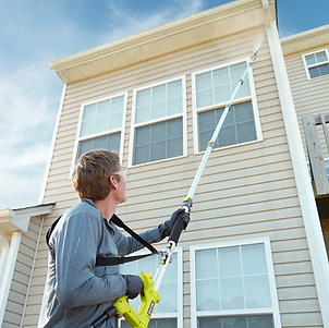 A man pressure washing the outside of a two story house