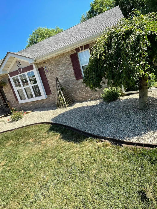 Home with tree and rock landscaping in front.