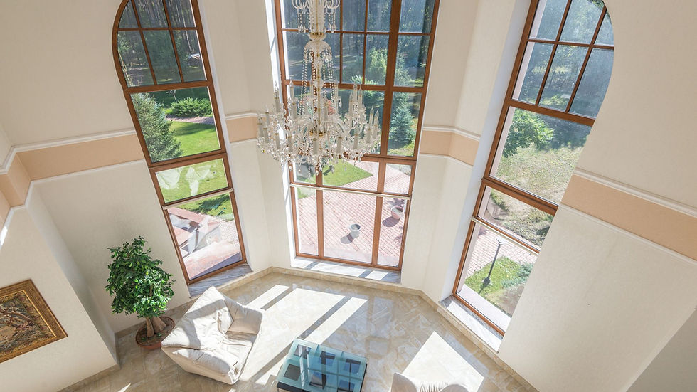 Spacious living area with floor-to-ceiling windows, elegant seating, and a grand chandelier.