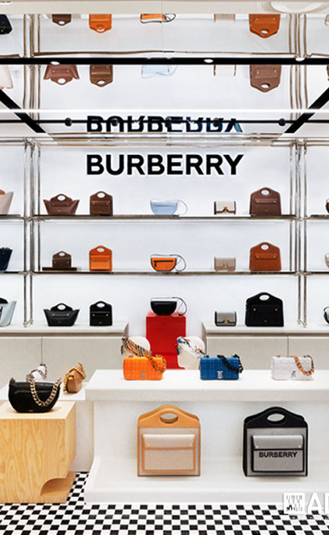 Close-up of Burberry handbag display on white shelving with mirrored ceiling, BURBERRY logo, and black and white checkered floor at Bal Harbour Shops