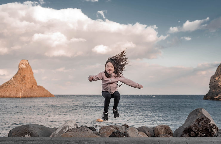 Conseils et astuces pour de meilleures photos de voyage - fille sautant devant un superbe océan en toile de fond