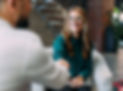 A smiling woman shaking hands with someone in a welcoming exchange