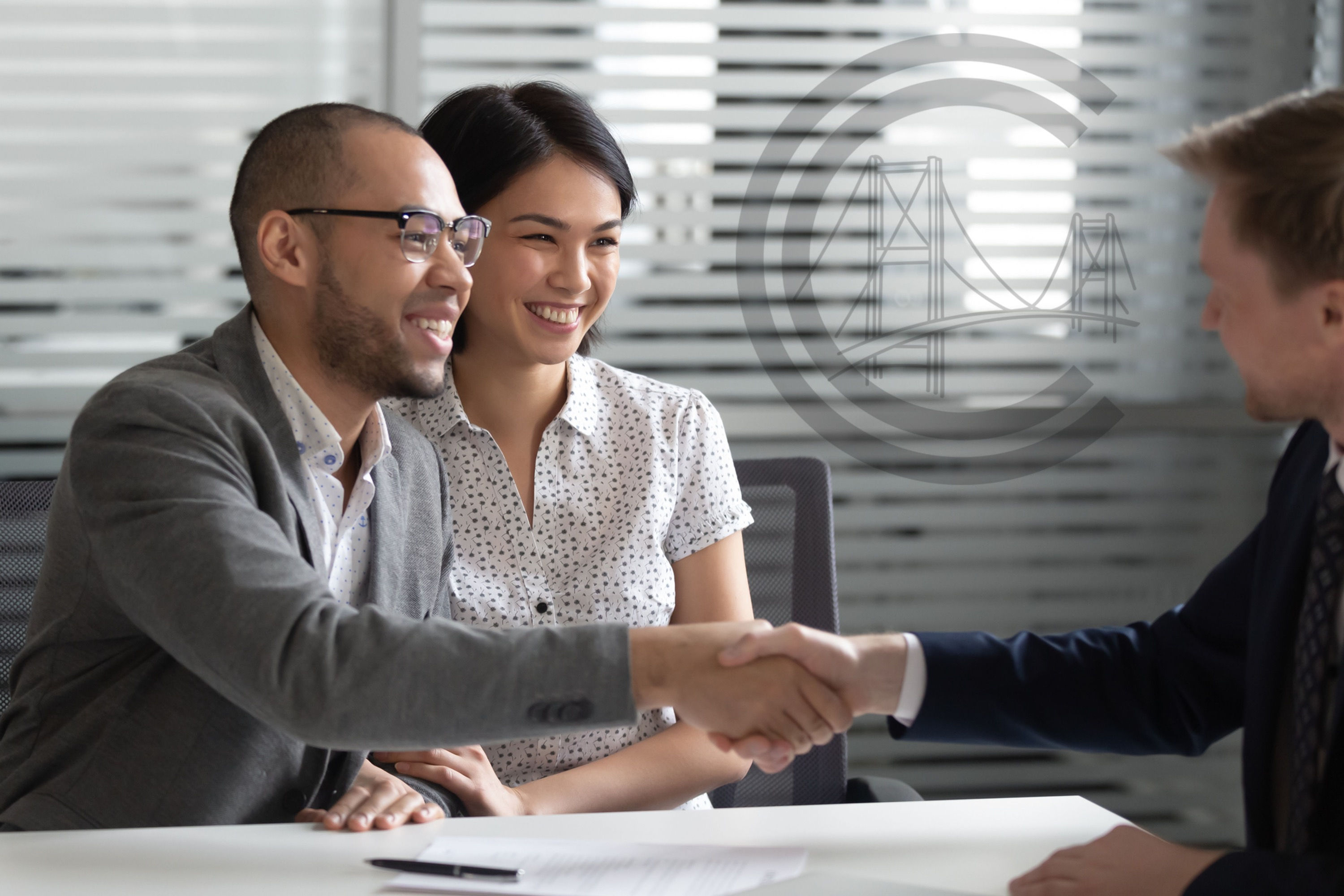 Two people on one side of the table, one of them shaking the hand of another person across the table.