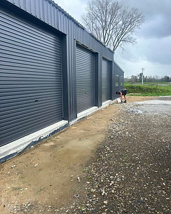 Dark garage doors, exterior view, and worker. Clothier Construction Services Waikato Putaruru.
