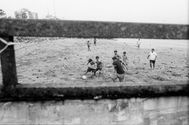 Children playing soccer on a sandy field