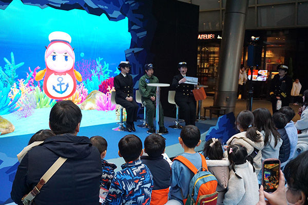 「鯛くん」と3人の海自隊員との「鯛トーク」。「仕事で世界中を回れる」「休暇がしっかりとれる」など、仕事の魅力を紹介した(写真はすべて3月8日、六本木ヒルズ・大屋根プラザで)