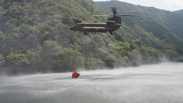 徳島県の火災現場に散水するため、香川県の川股ダムで取水する陸自CH47大型輸送ヘリ（8月30日）＝14旅団提供
