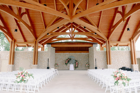 a wedding setup of many chairs under a pavilion outside