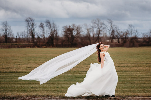 bride trying to hold onto her veil on a windy day