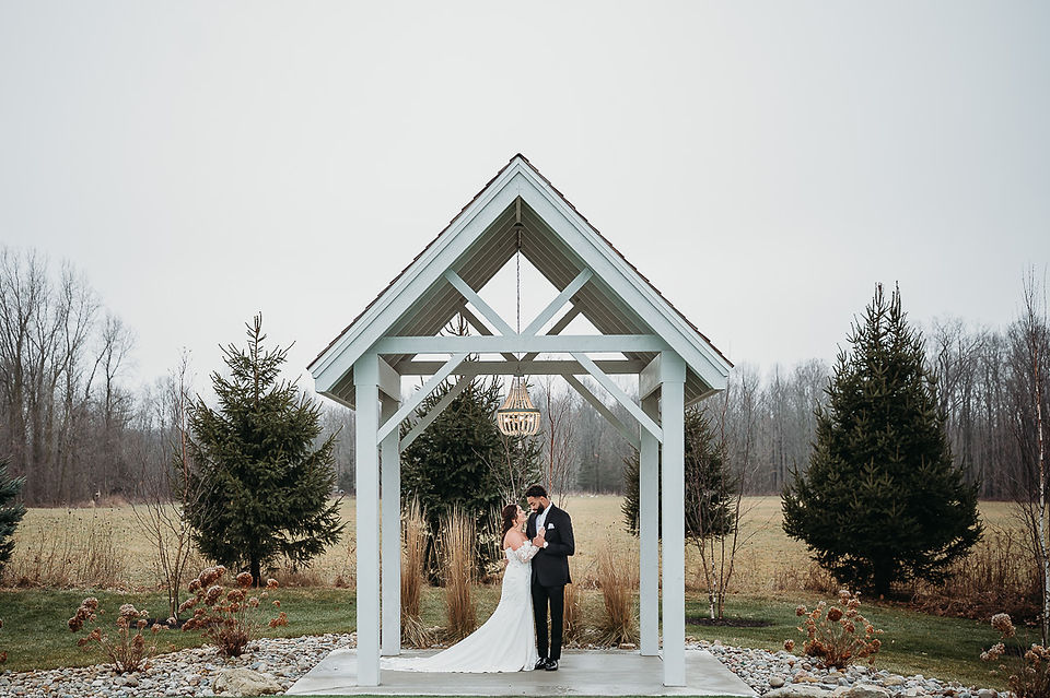 bride and groom standing under a wedding venue arch at White Birch Wedding Barn