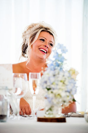 Bride smiling at the head table inside the wedding marquee at Parley Manor