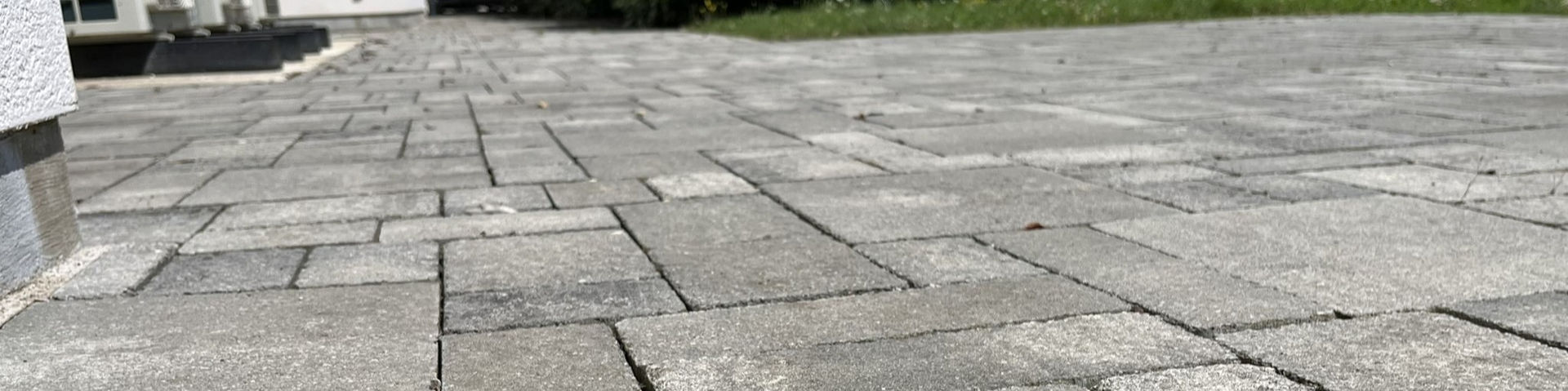 Vue très zoomée d'une allée en pavé ou en pierres, surfacée avec des pierres grises et bordée de végétation