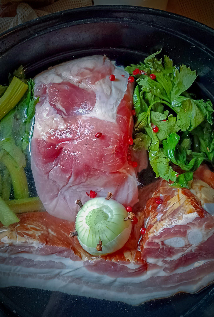 plat copieux de potée au chou et petit salé. Le plat comprend des morceaux de viande salée, des carottes, des haricots blancs et du chou, le tout servi dans un pot en céramique rustique. Les couleurs et textures vibrantes des ingrédients rendent le plat appétissant et réconfortant, parfait pour un repas en famille.