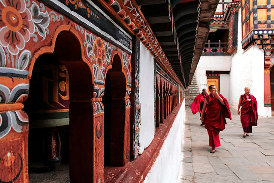 Buddhist monk in traditional red robes walking through a serene Bhutanese monastery courtyard