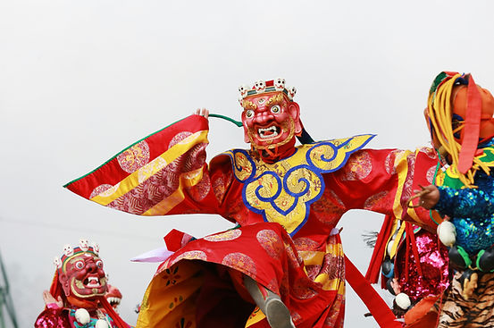 Masked dancers in colorful costumes perform sacred cham dances at Thimphu Tshechu festival, Bhutan