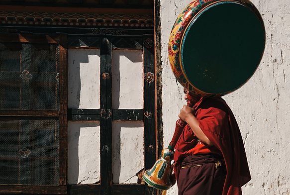 Buddhist monk in Bumthang, Bhutan carrying a traditional ceremonial drum outside a monastery – cultural and spiritual Bhutan