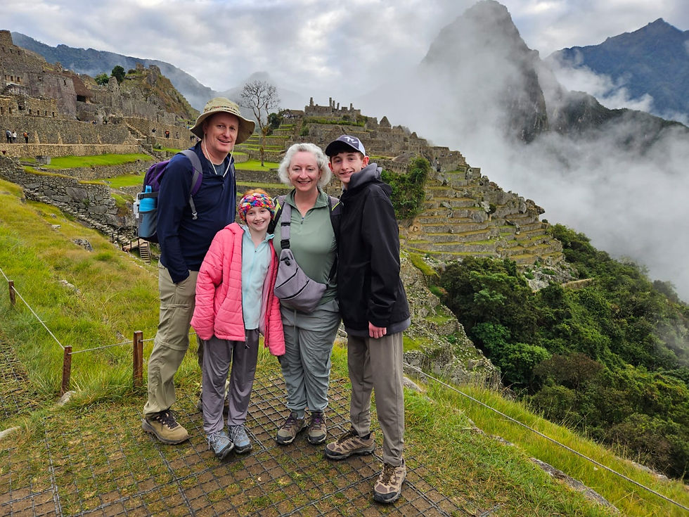 A group of travelers enjoys a misty day exploring the ancient ruins of Machu Picchu in Peru.