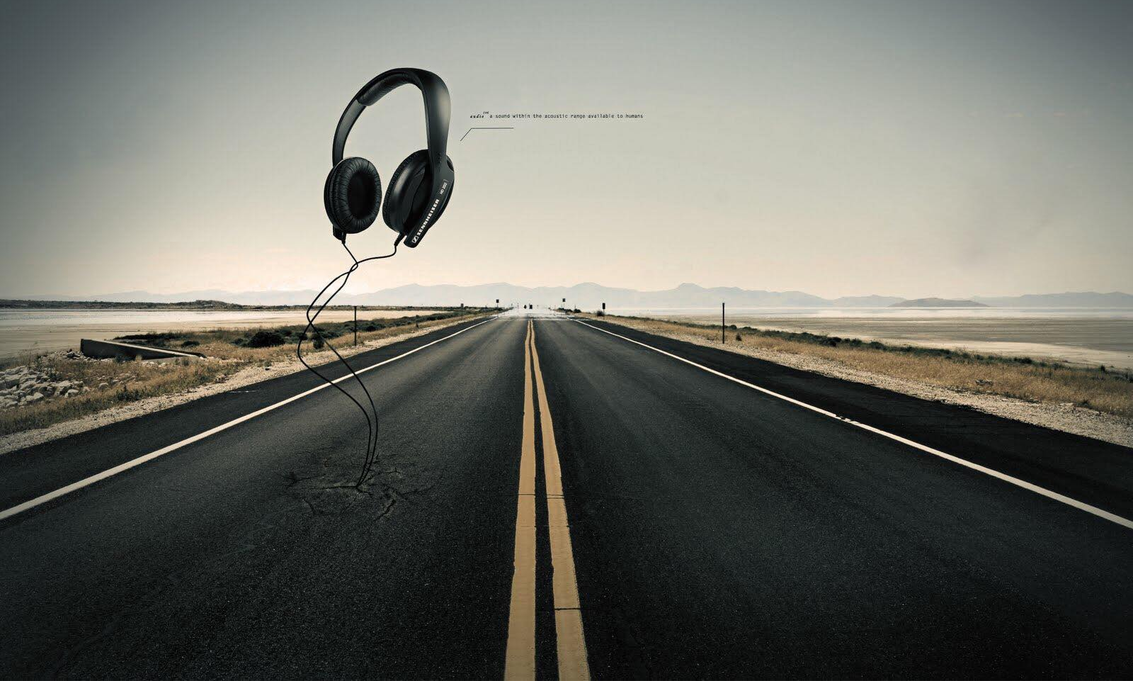 An empty road running to the horizon with a pair of headphones floating above it