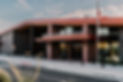Prescott Regional Airport entrance with large sign, modern design, and glass doors. An American flag flies nearby under a partly cloudy sky.