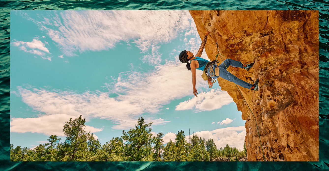 Woman rock climbing on an orange cliff in Arizona.