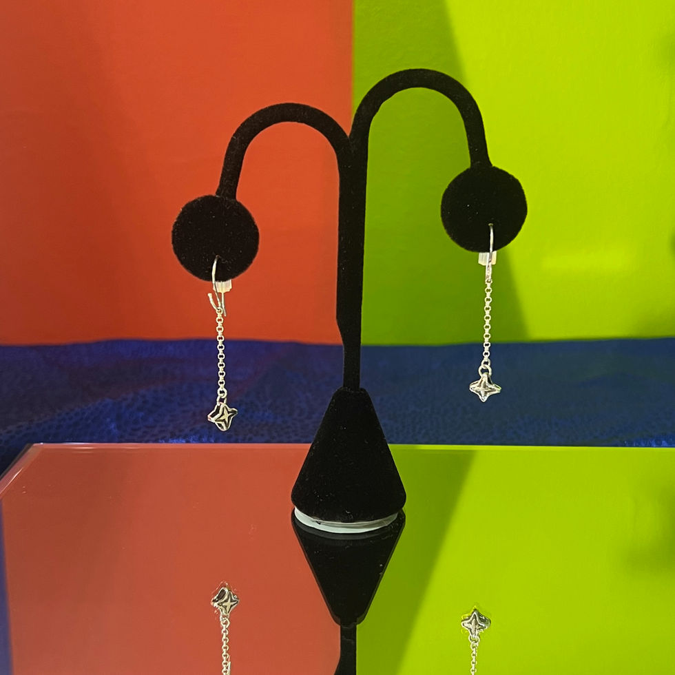 a pair of silver earrings are displayed on a black stand