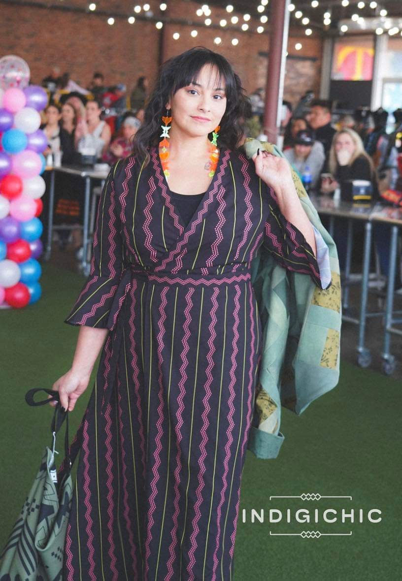 a woman in a striped dress is holding a green bag
