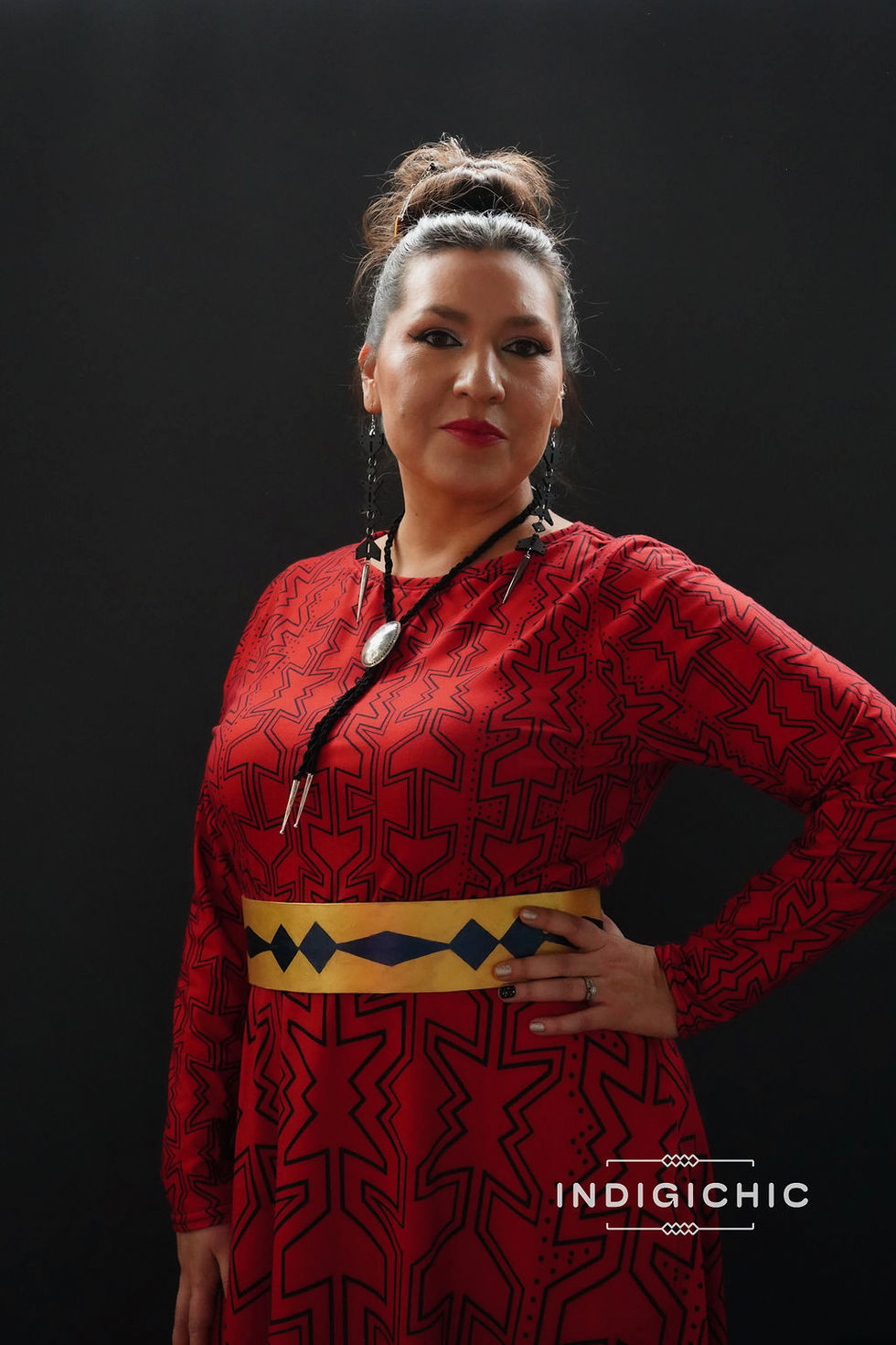 a woman wearing a red dress and a necklace has her hand on her hip