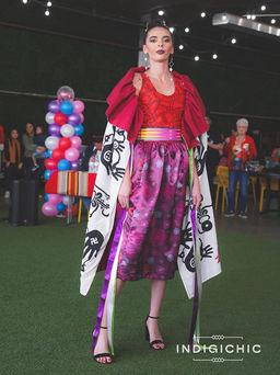 a woman wearing a red top and purple skirt is standing in front of balloons