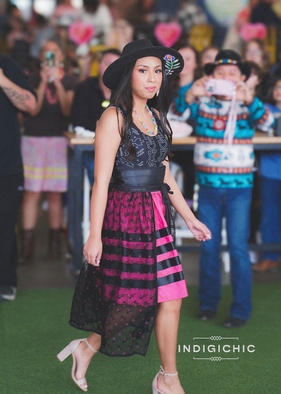 a woman wearing a black hat and a pink and black dress